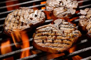 Grilled pork steak on the flaming grill