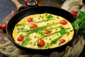 Omelette (omelet) with tomatoes, asparagus and green onions